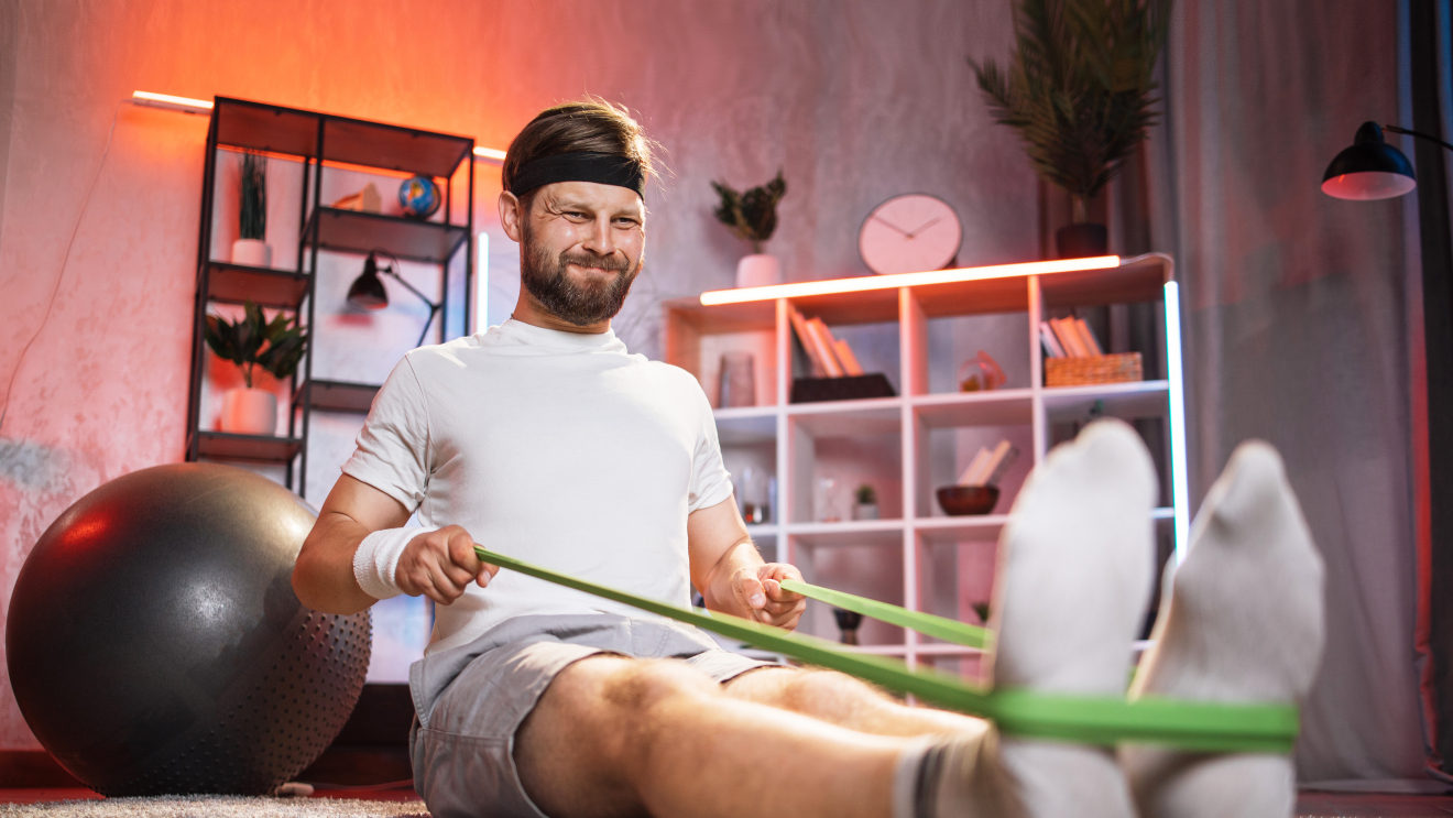 Mann trägt Stirnband und macht mit Gummiband ein Workout